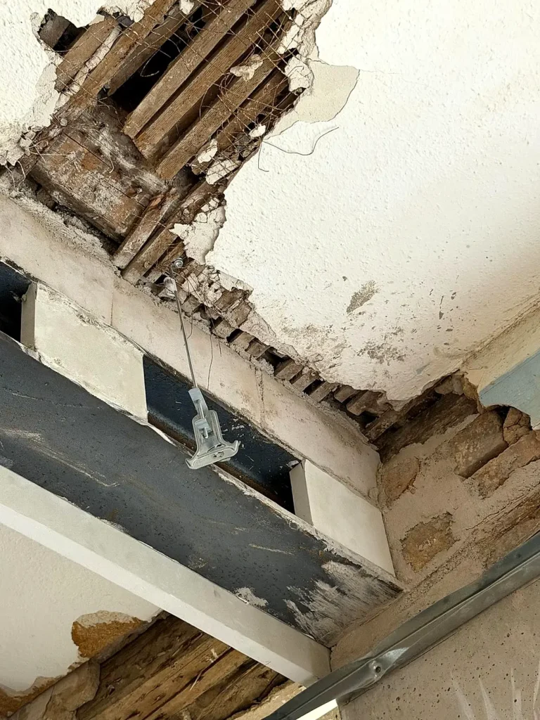 Neuer Stahlträger neben freigelegter Holzbalkendecke